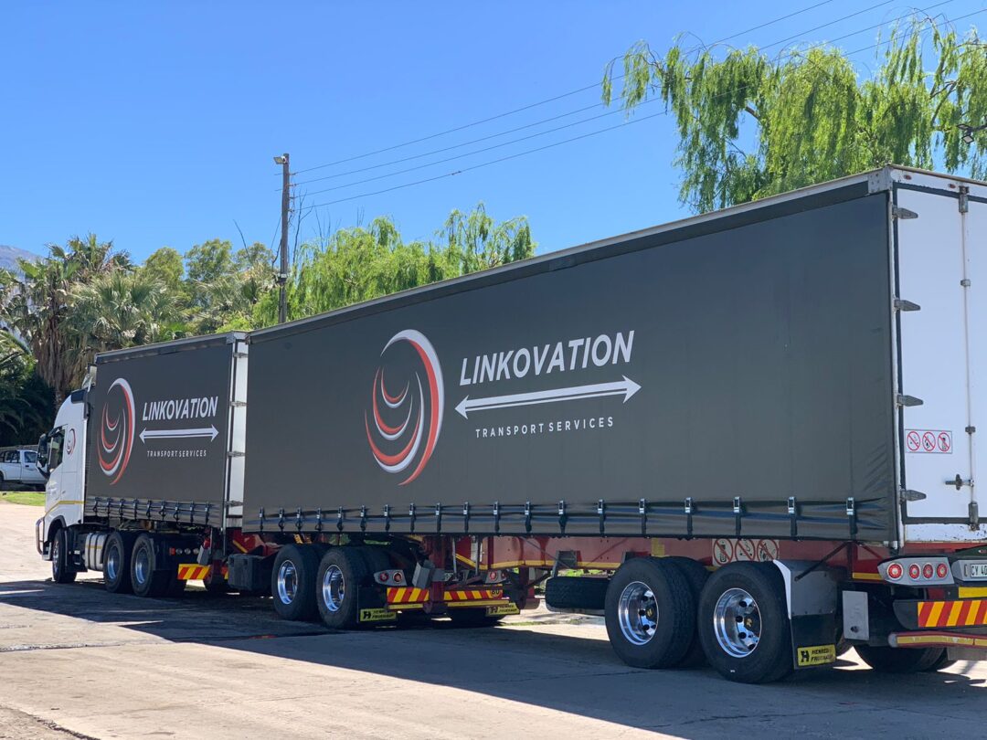 Black Linkovation Transport Services truck with double trailer on highway